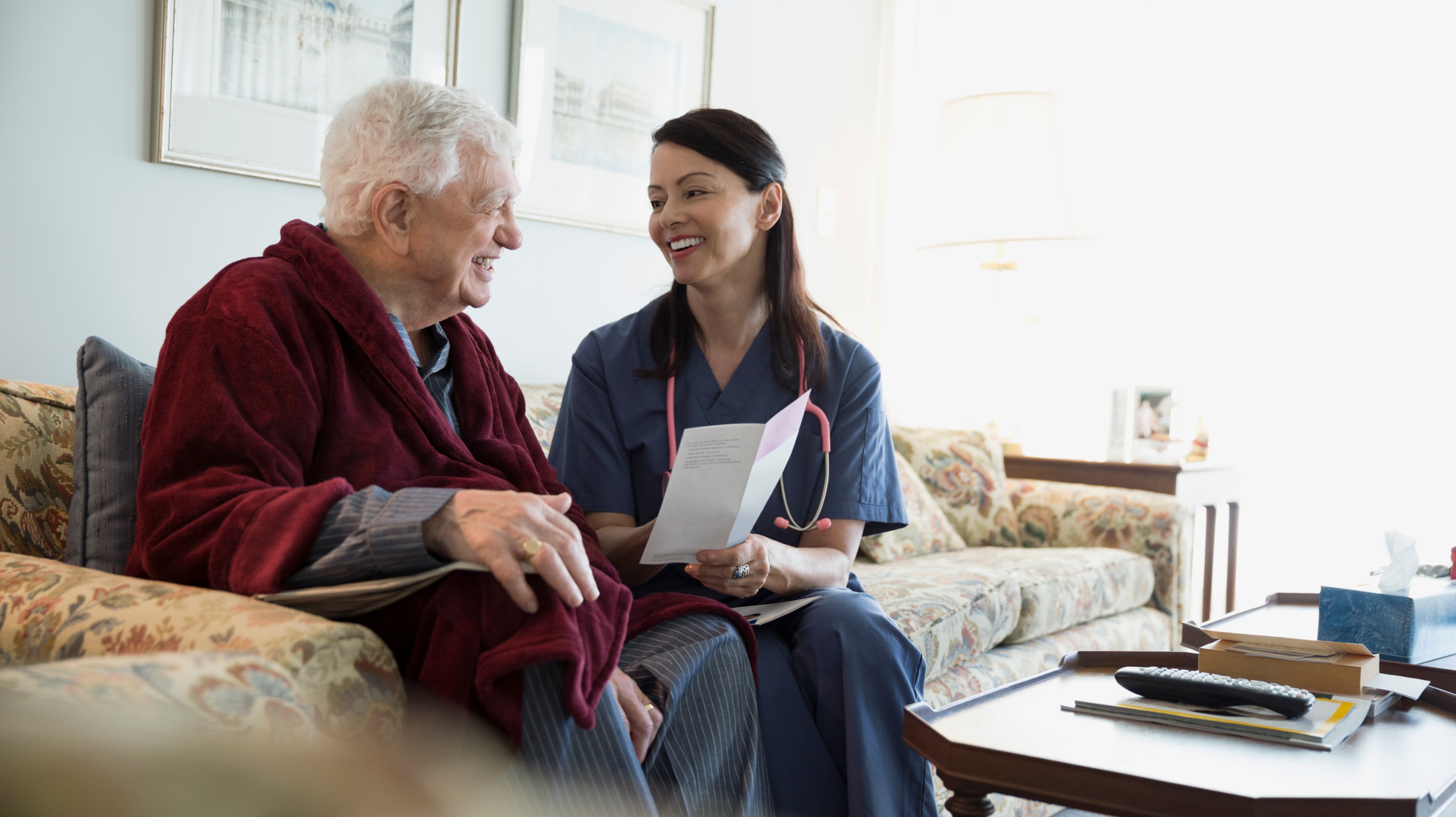 man on couch next to nurse explaining paperwork