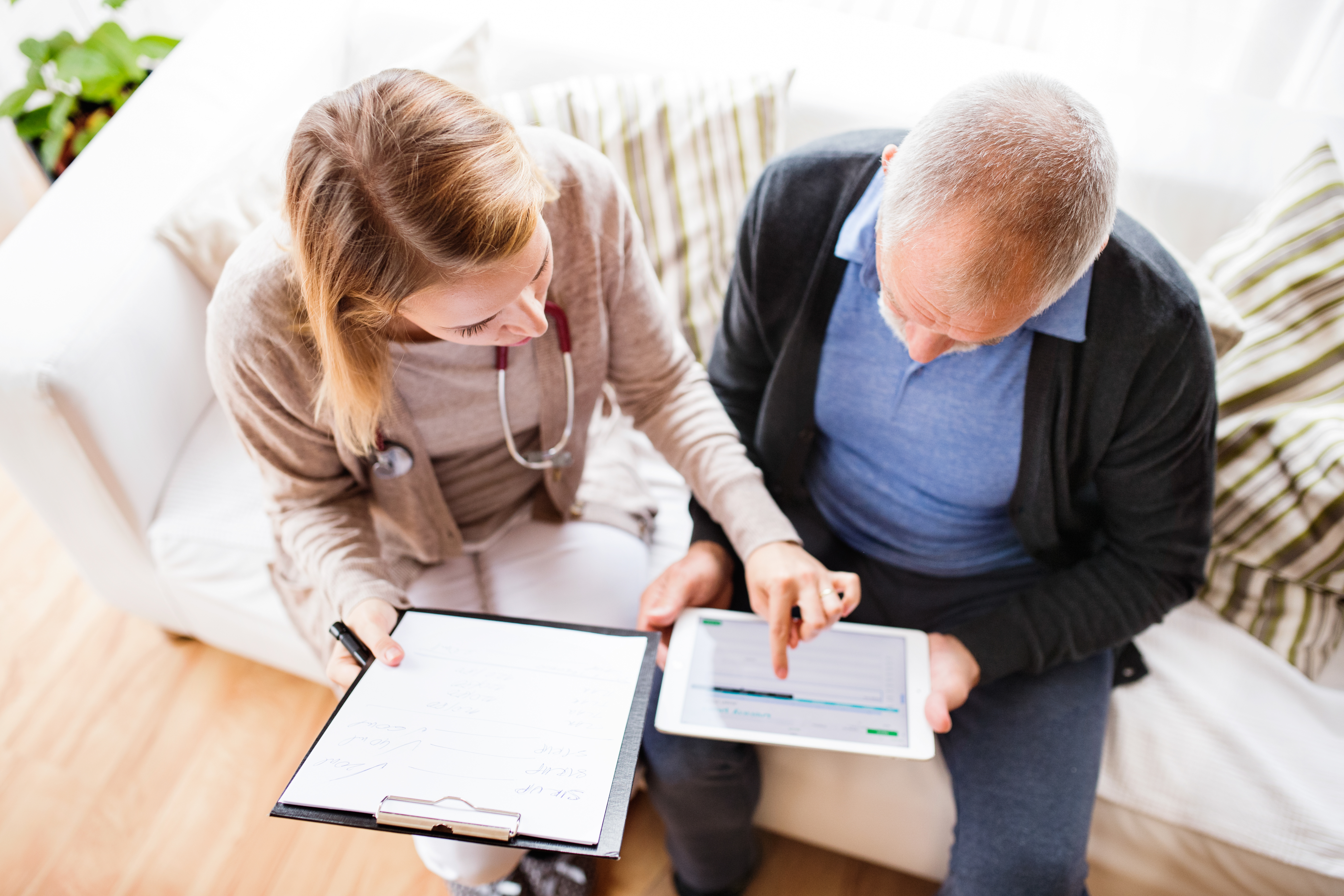 health visitor and a senior man with tablet during home visit
