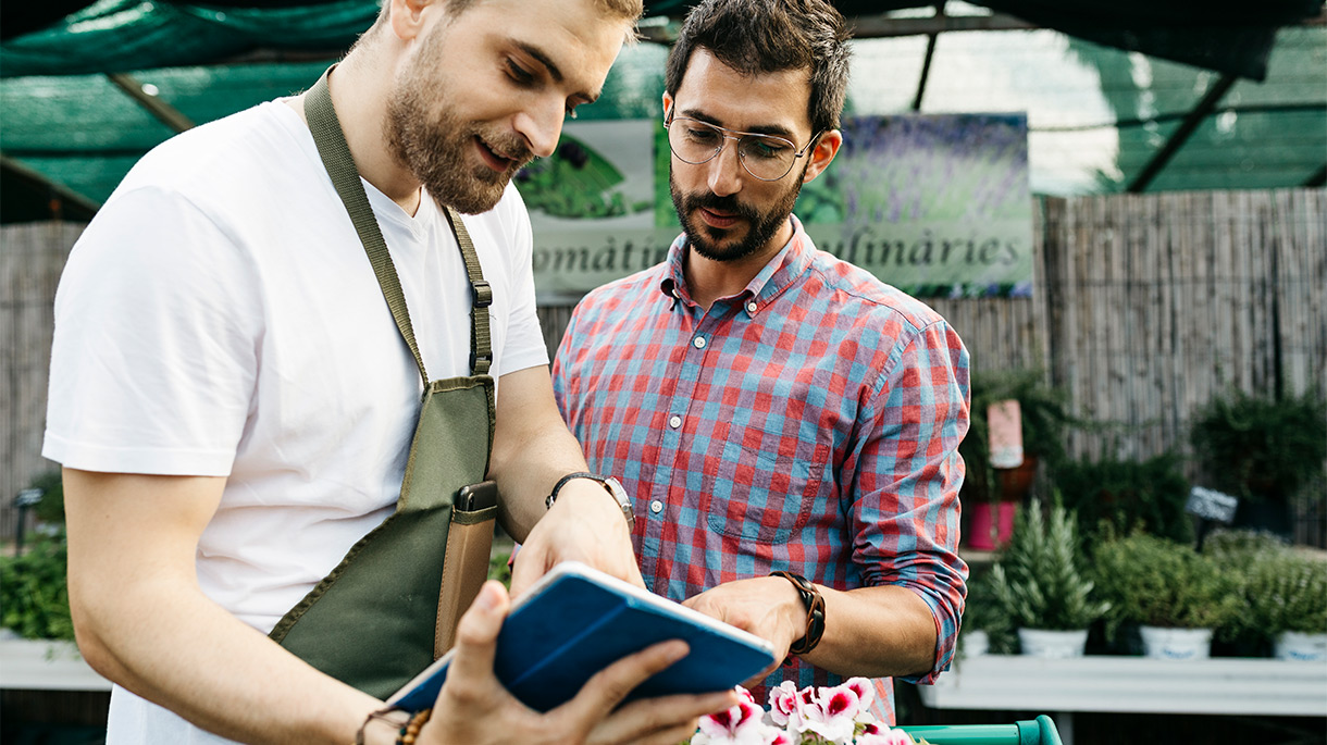 two men looking at tablet in a greenhouse