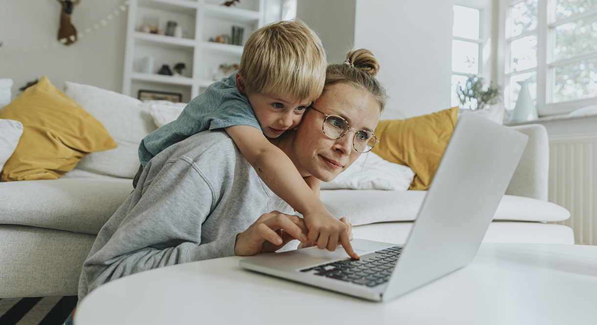 Child overlooking parent's shoulder on a laptop