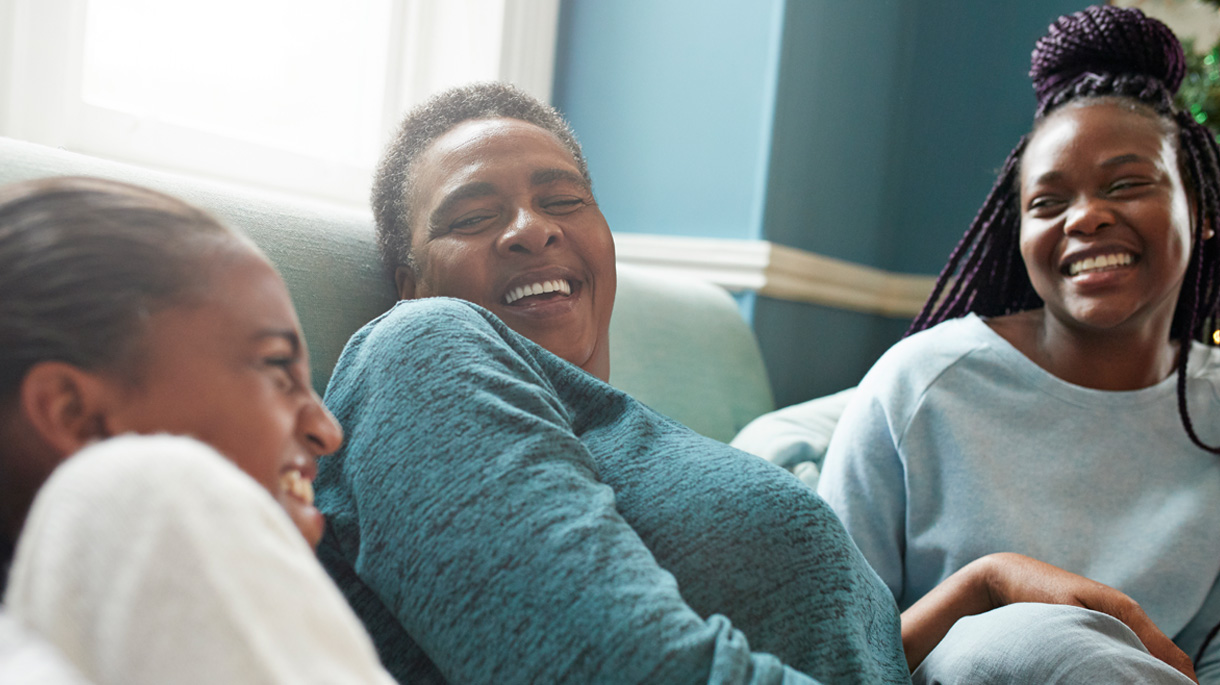 Three people smiling and laughing with each other at home