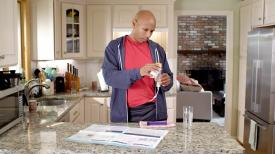 A man prepares formula for tube feeding in his kitchen.